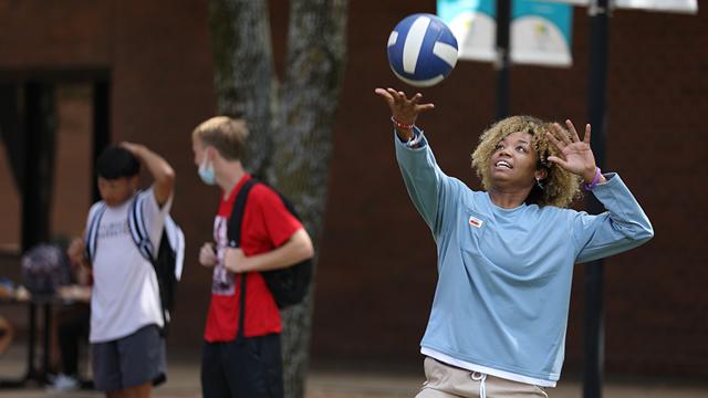 Three students playing recreational volleyball